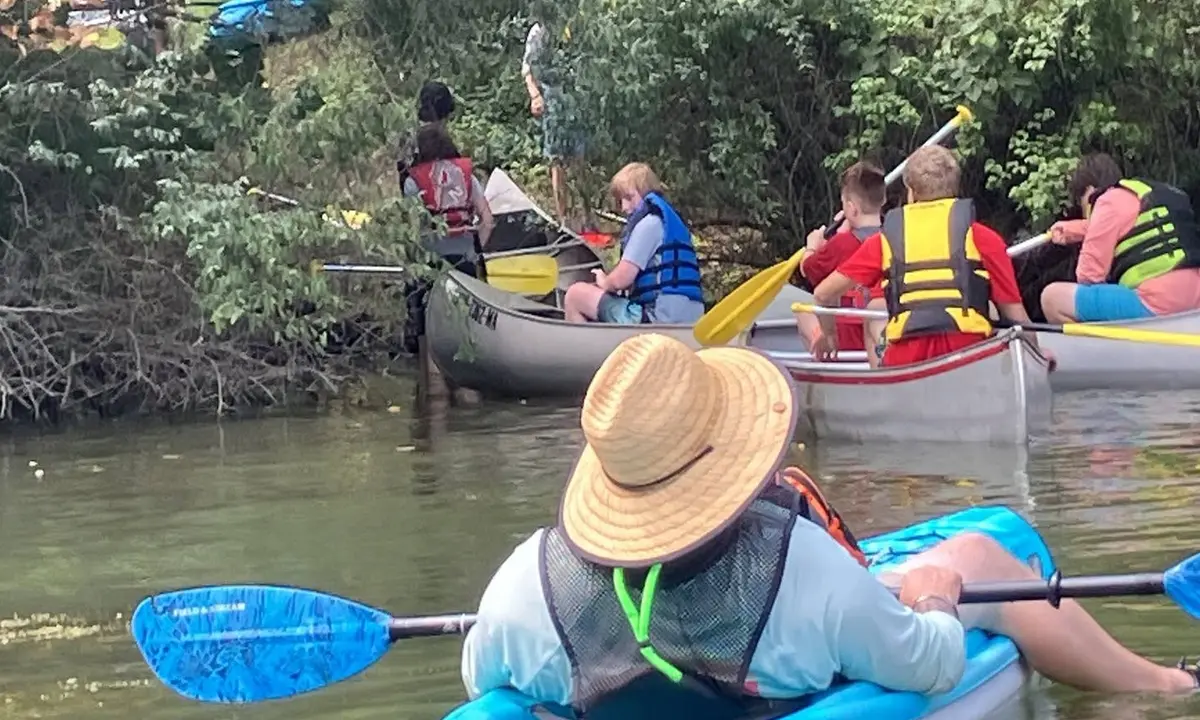 An adult leader paddling behind Troop 826 Scouts during a canoe trip