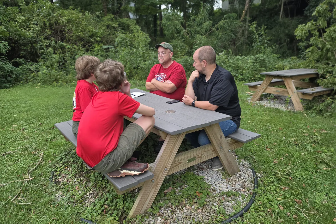 Scouts and an adult leader talking at a picnic table
